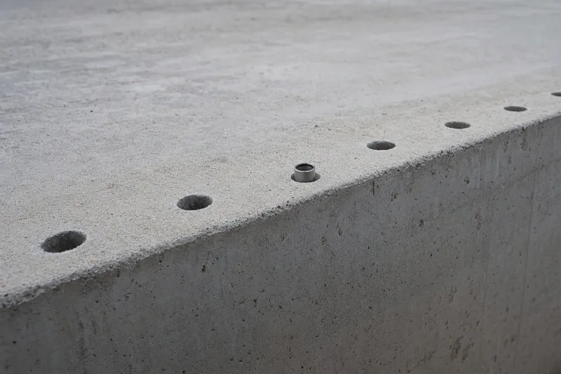 The edge of a concrete block with a row of drilled holes along its top and a steel ring fitted in one of them — resin injection, Newcastle. Illustrative example.